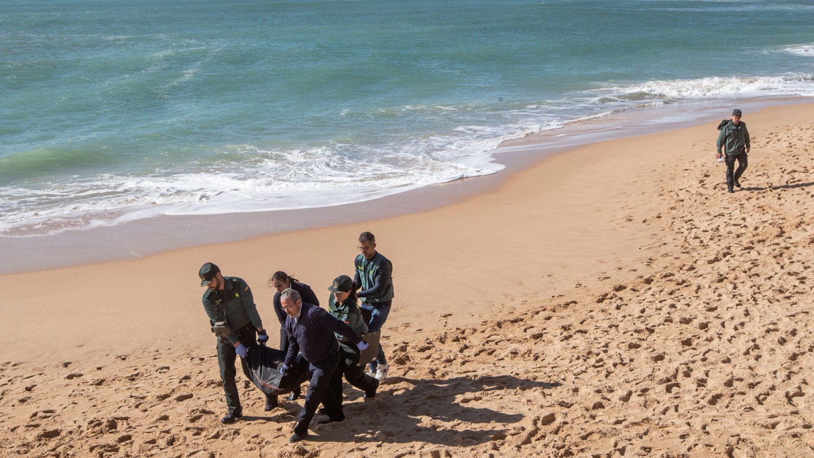 Agentes de la Guardia Civil trasladan un cadáver hallado de la patera que naufragó en la playa de Caños de Meca (Cádiz)