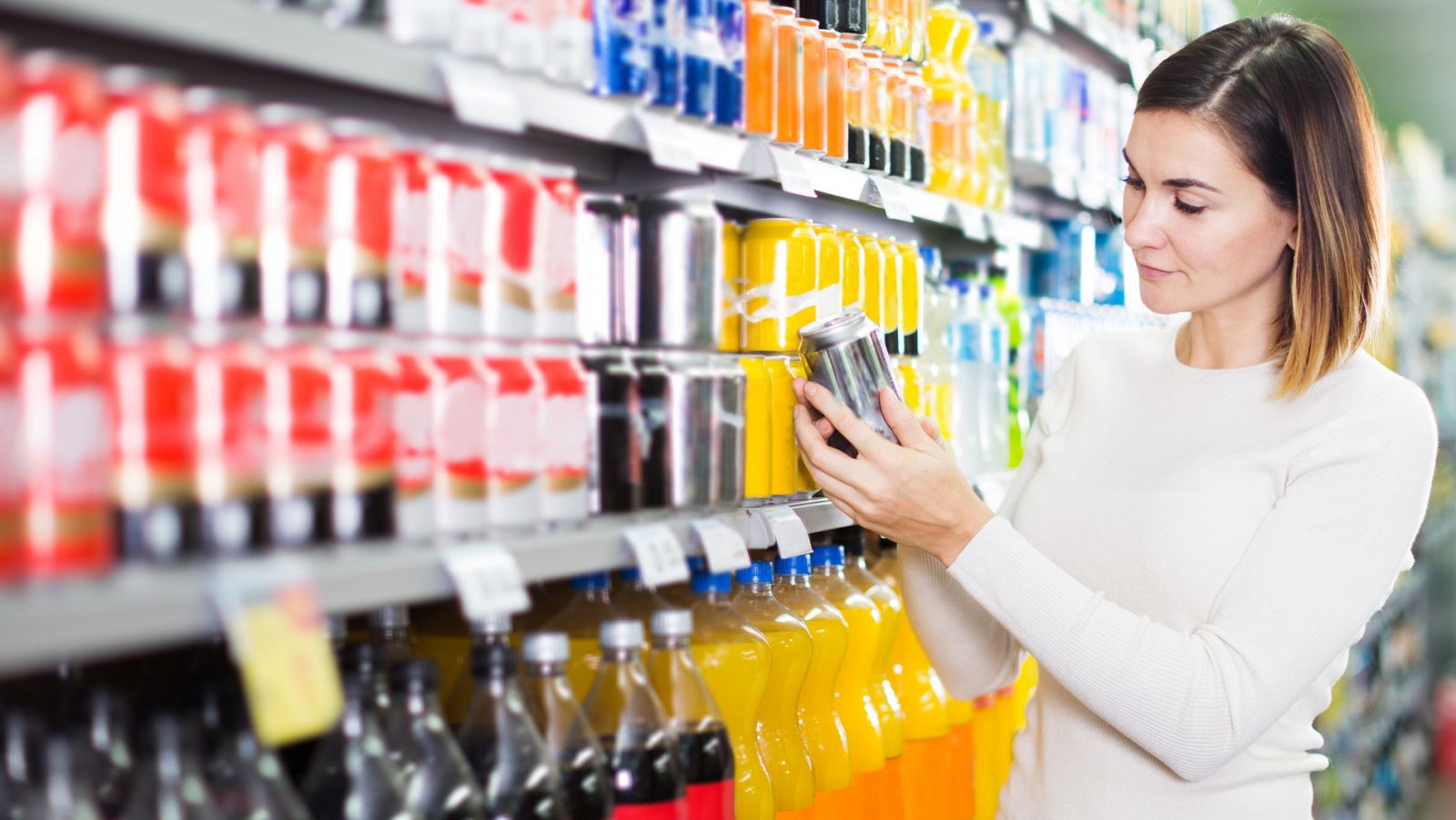 Una mujer mira la etiqueta de un refresco en un supermercado.