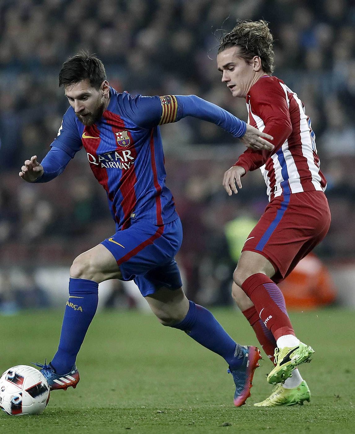 El delantero del FC Barcelona Leo Messi (i) controla el balón ante el del Atlético de Madrid Antoine Griezmann durante un partido de 2017
