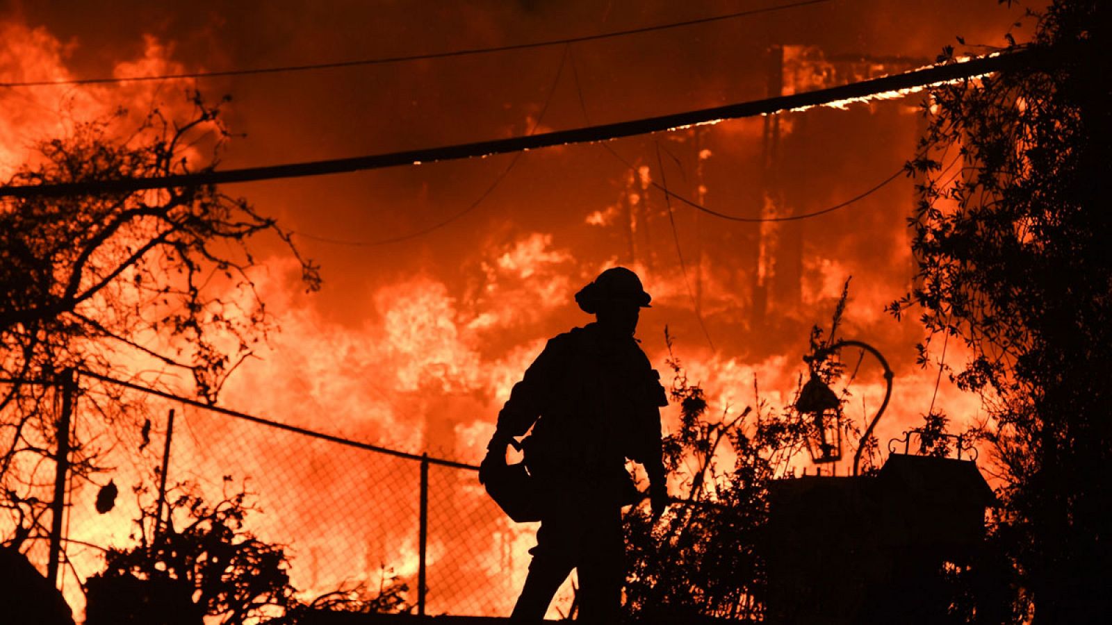 Imagen de un bombero frente una casa en llamas como consecuencia de un incendio forestal en Malibú, California.