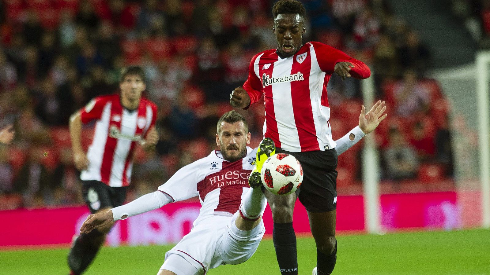 El delantero del Athletic de Bilbao, Iñaki Williams disputa un balón con el defensa serbio del SD Huesca, Rajko Brezancic.