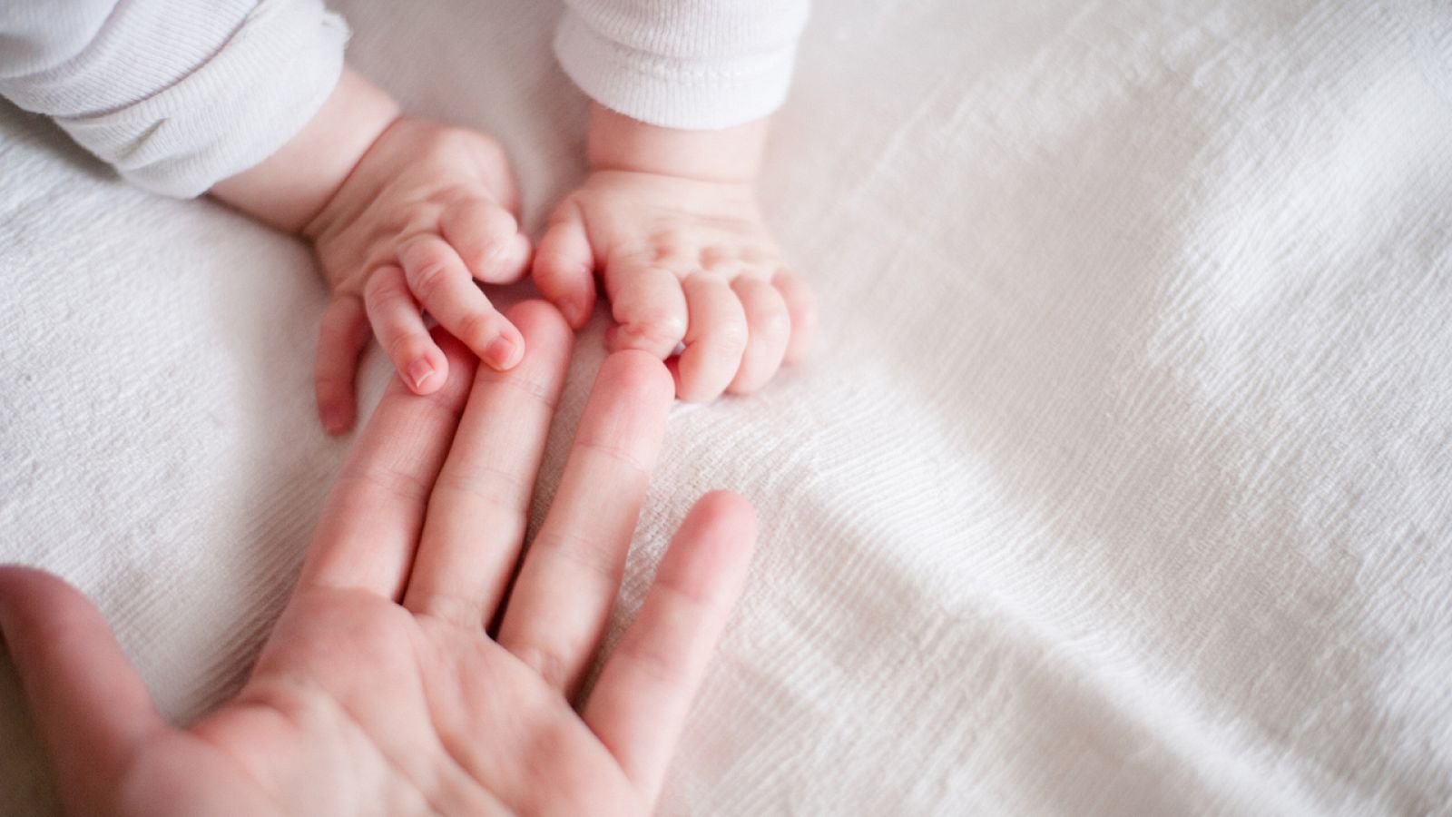 Fotografía de recurso de una madre dando la mano a su bebé
