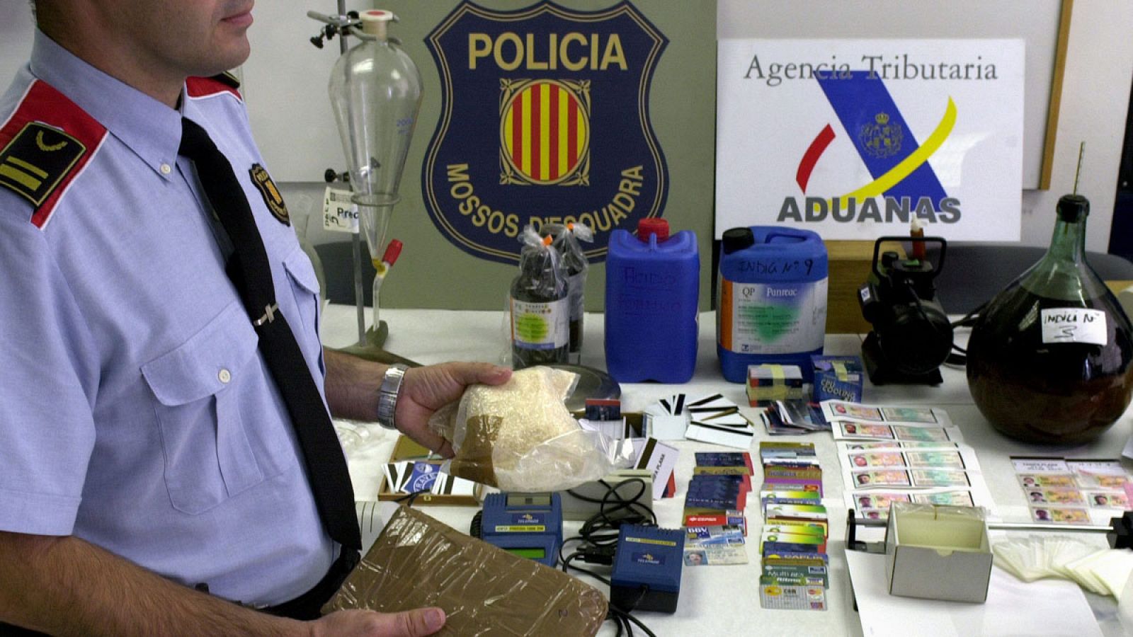 Un policia autonómico muestra dos paquetes, uno de hachís y otro de droga sintética, en una imagen de archivo.