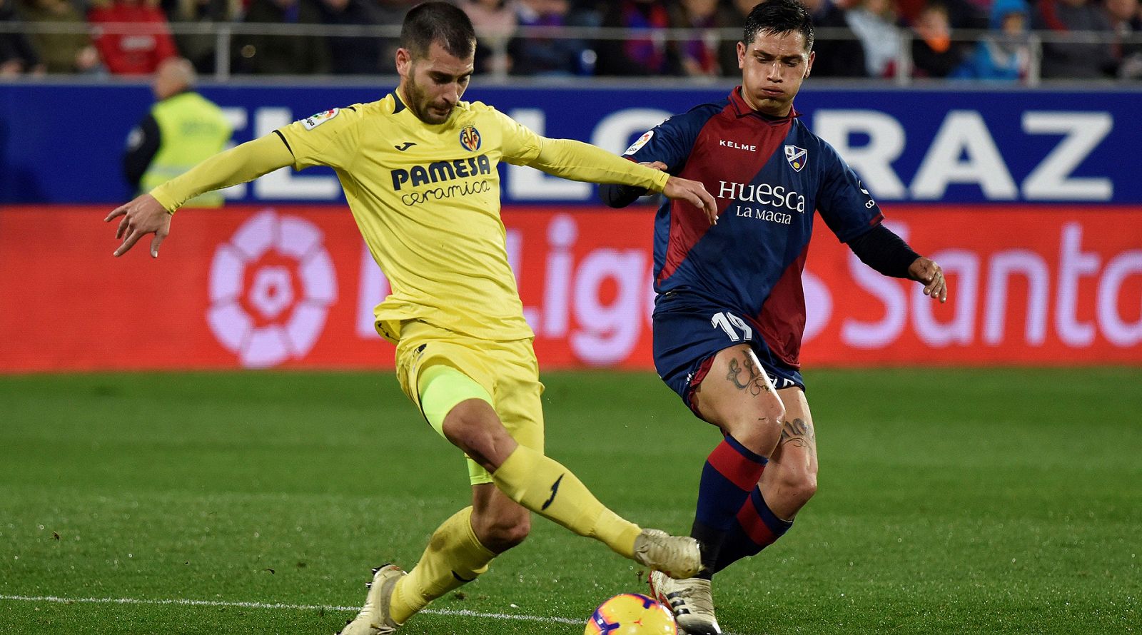 El delantero argentino del SD Huesca, Ezequiel Ávila, lucha por el balón frente al centrocampista del Villarreal CF, Manu Trigueros.