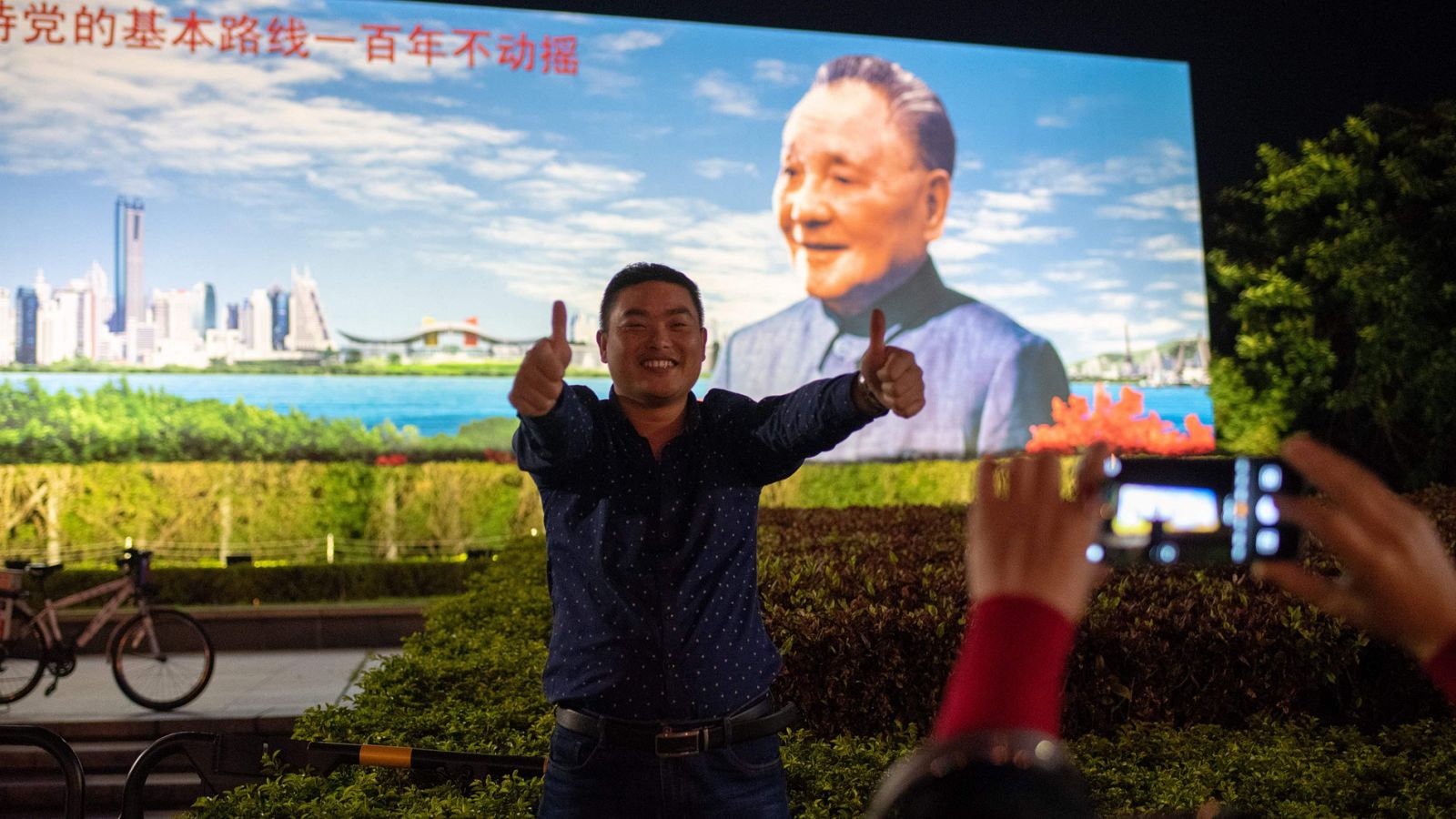 Un ciudadano chino posa junto a un cartel con la imagen de Deng Xiaoping en Shenzhen, China