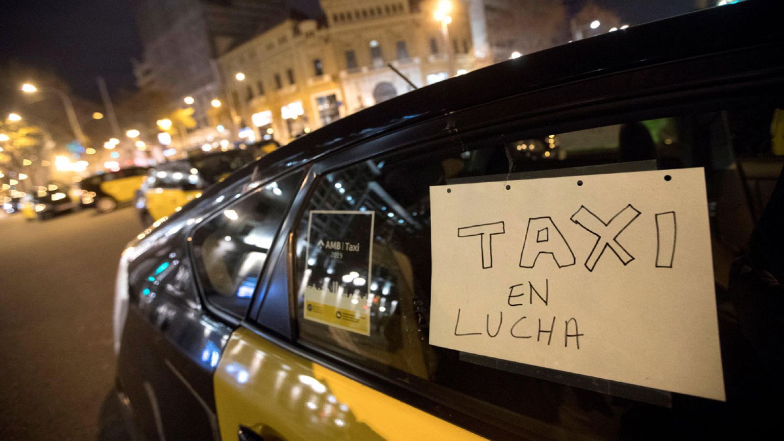 Imagen de un taxi con un cartel en el que se lee "Taxi en lucha" en una calle de Barcelona.