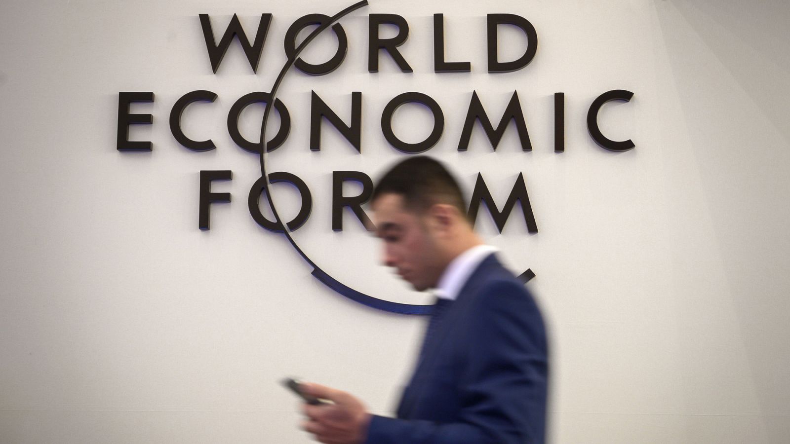 Un hombre camina frente a un logotipo del Foro Económico Mundial en el centro de congresos de Davos