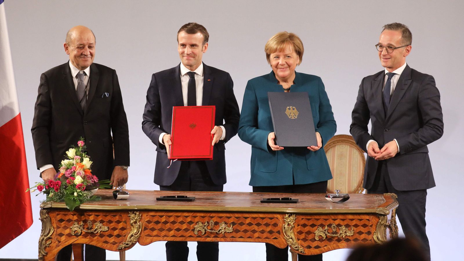 El presidente francés, Emmanuel Macron, y la canciller alemana, Angela Merkel sostienen el tratado bilateral firmado por ambos