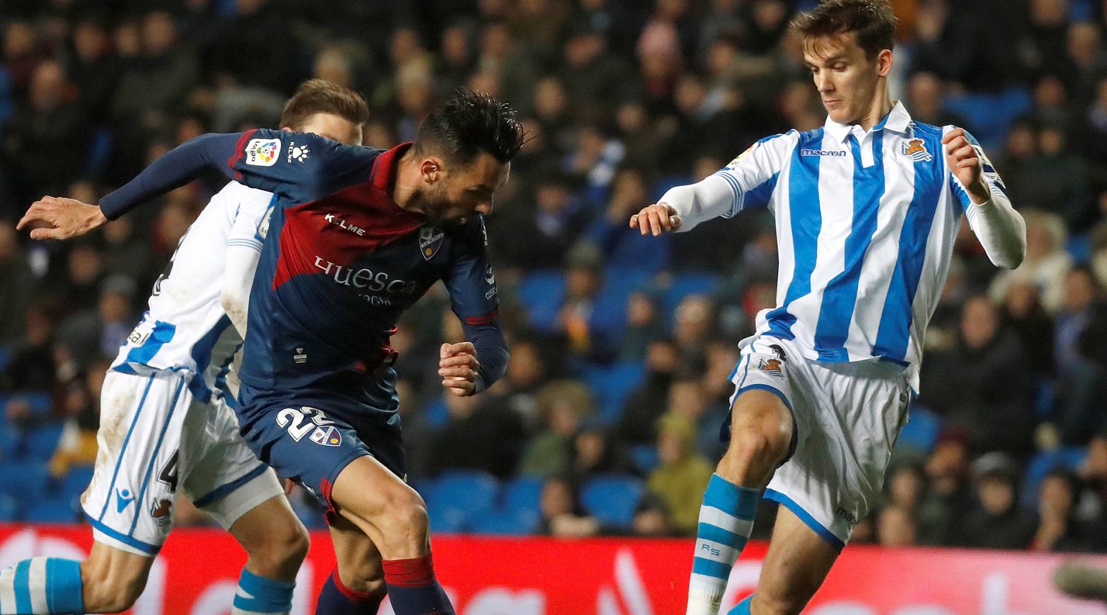 El jugador de la Real Sociedad, Diego Llorente, lucha un balón con Enric Gallego, del Huesca.