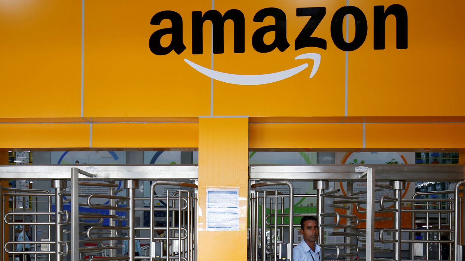 Un empleado camina frente a un almacén de Amazon
