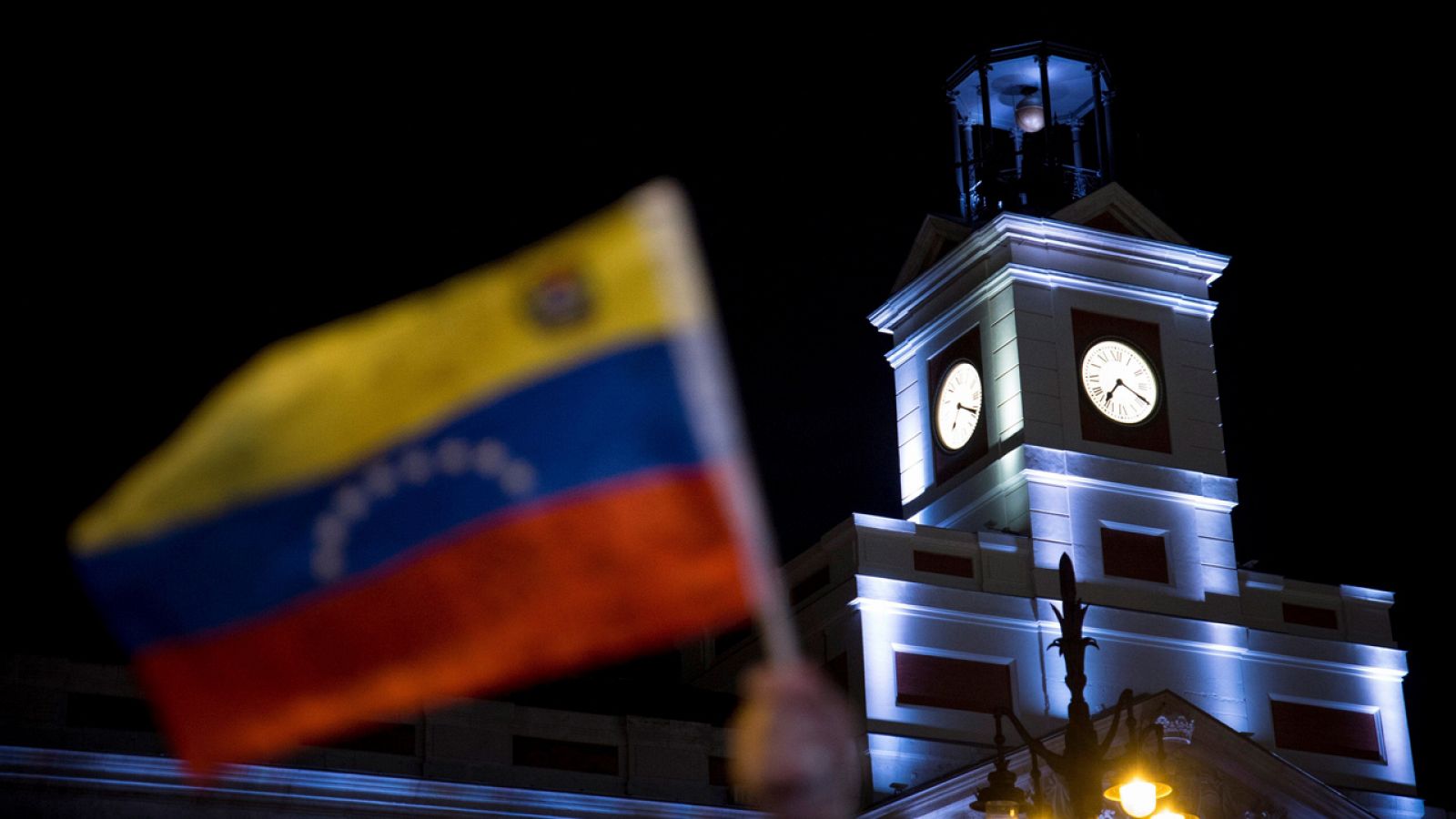 Manifestantes opositores ondean la bandera de Venezuela en la Puerta del Sol