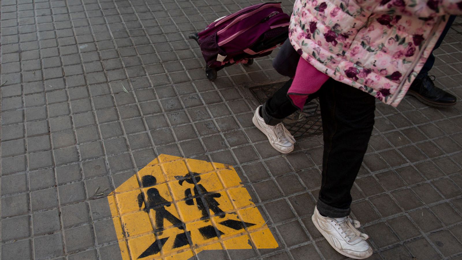 Niños caminando con mochila de ruedas.