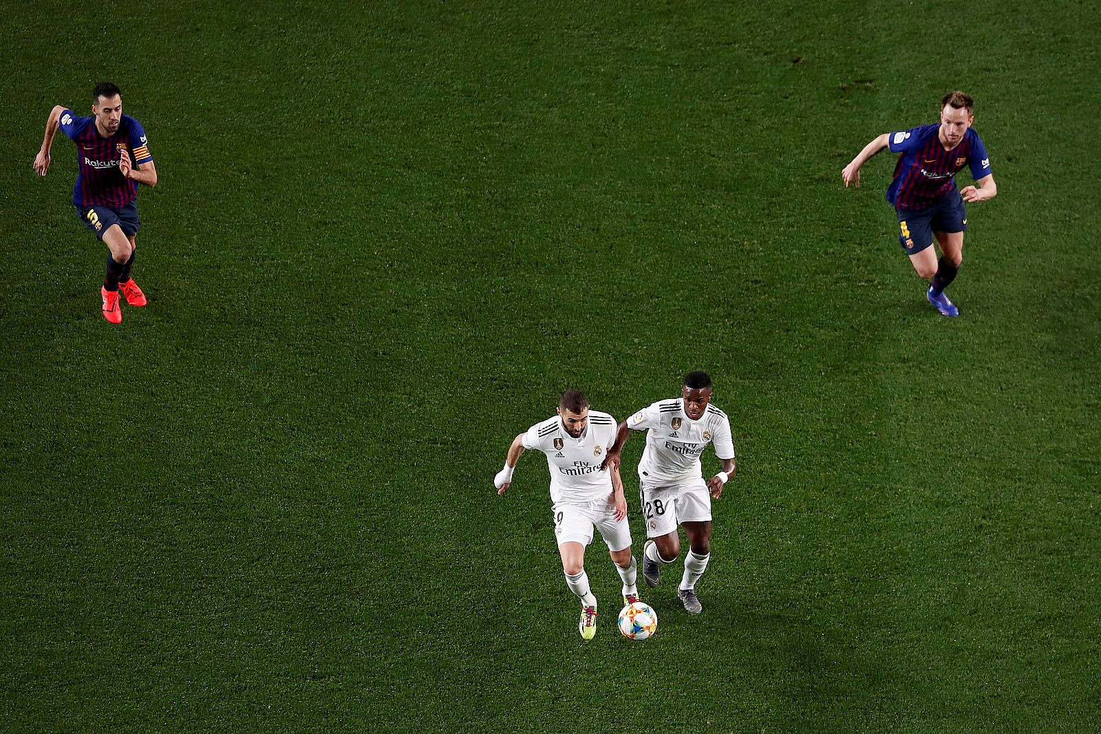 Los delanteros del Real Madrid Benzema (i) y Vinicius, se escapan con el balón de Busquets (i) y Rakitic en el partido de ida de las semifinales de la Copa