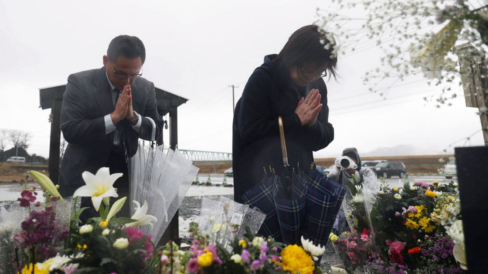 Dos personas rezando por las víctimas del 11 de marzo de 2011 en Japón.