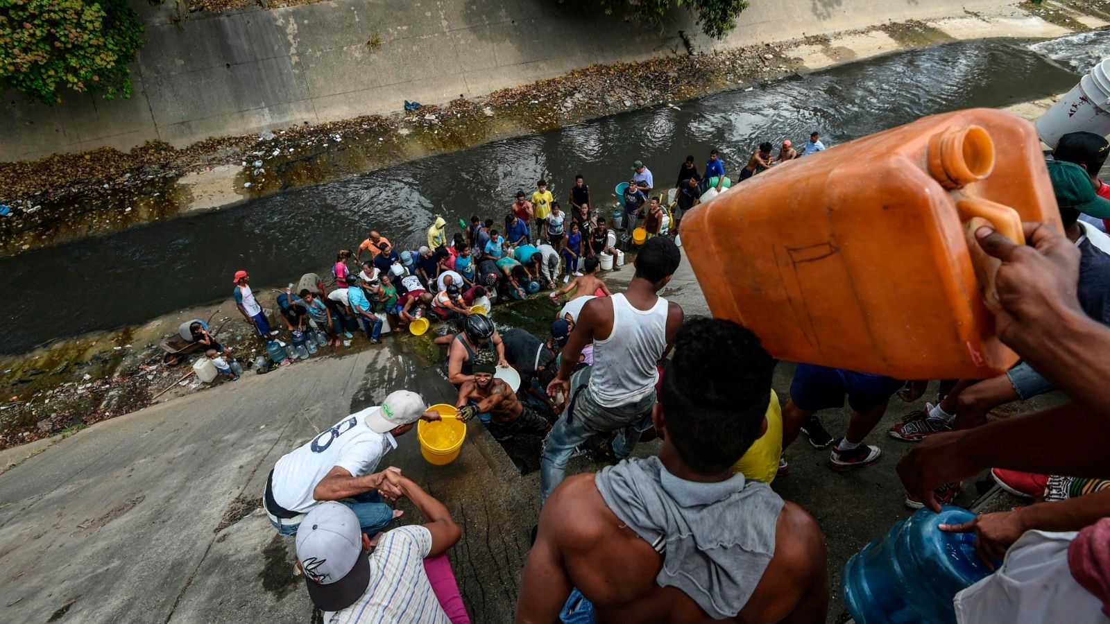Un grupo de personas recoge agua de un canal en Caracas tras el apagón en Venezuela