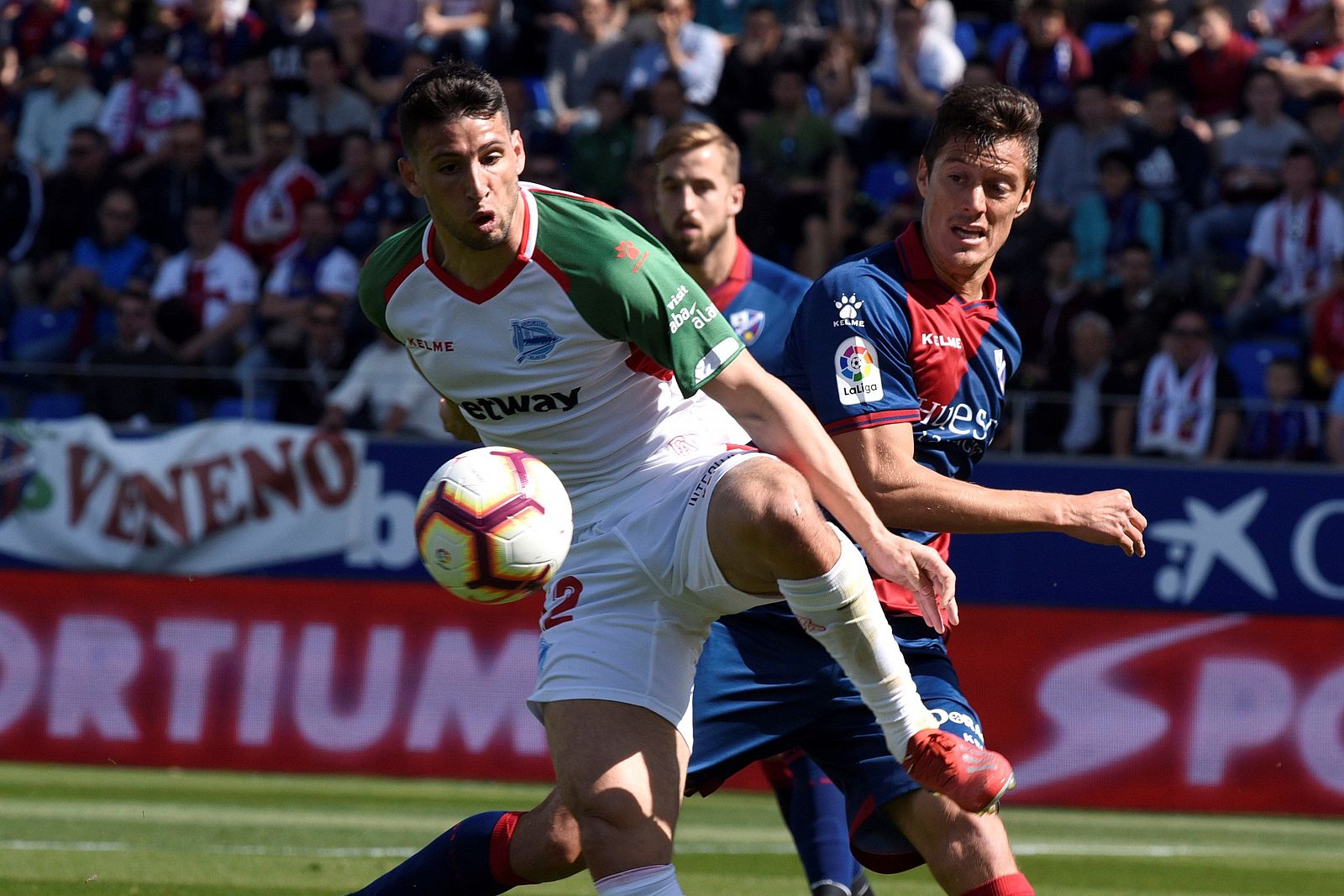 El delantero argentino del Alavés Jonathan Calleri (i) controla el balón ante la oposición del defensa argentino del Huesca Martín Mantovani (d) durante el partido de Liga