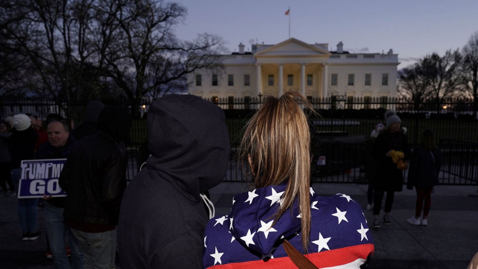 Una mujer con una chaqueta con la bandera de los Estados Unidos frente a la verja de la Casa Blanca en Washington, EE.UU.