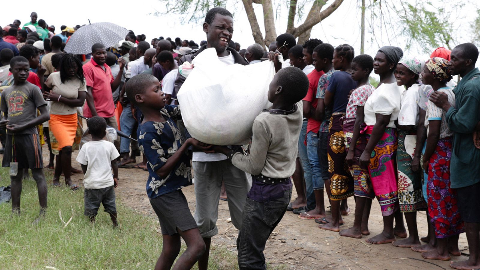 Un hombre y dos niños recogen donaciones después del paso del ciclón Idai en la provincia de Sofala, en el centro de Mozambique