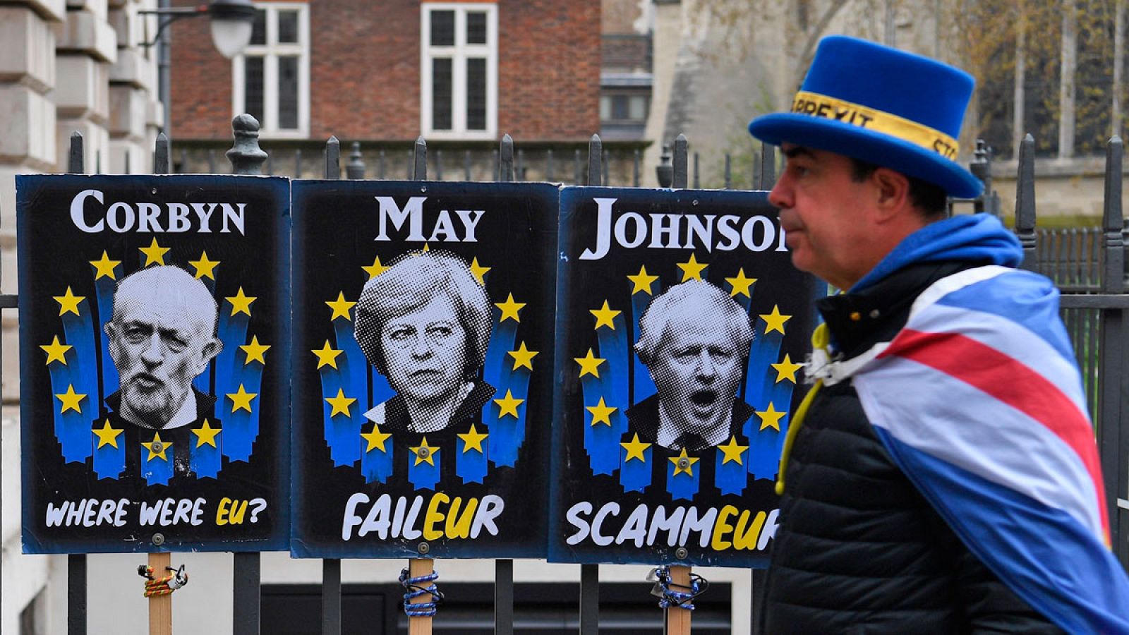 Un manifestante a favor de la estancia del Reino Unido en la Unión Europea camina junto a carteles que critican a Jeremy Corbyn, Theresa May y Boris Johnson en Londres.