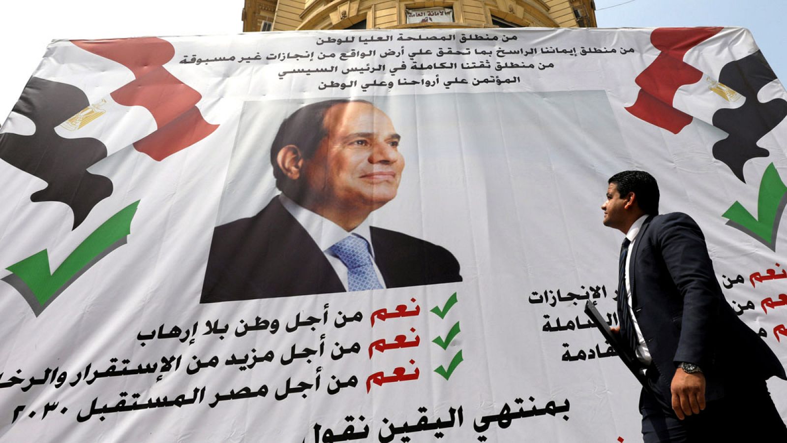 Un hombre camina delante de un cartel en el que aparece el presidente egipcio, Abdelfatah al Sisi.