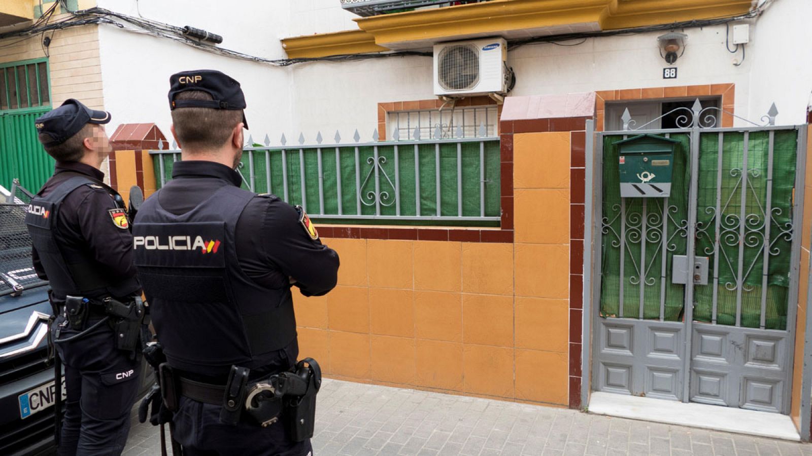 Dos agentes de la Policía Nacional delante de la casa de Sevilla donde residía el presunto yihadista