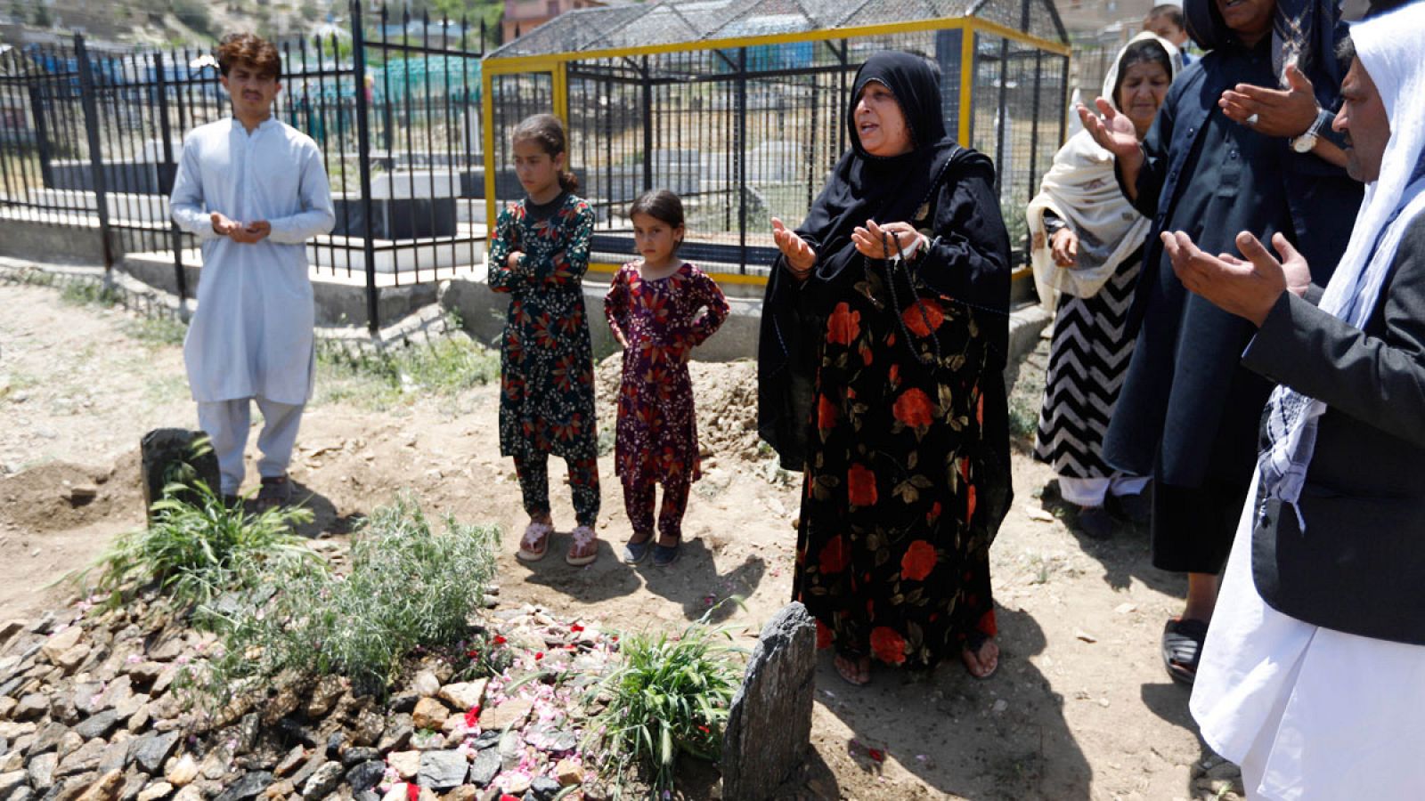 La madre (C) de la difunta periodista y asesora política afgana Mena Mangal reza frente a la tumba de su hija.