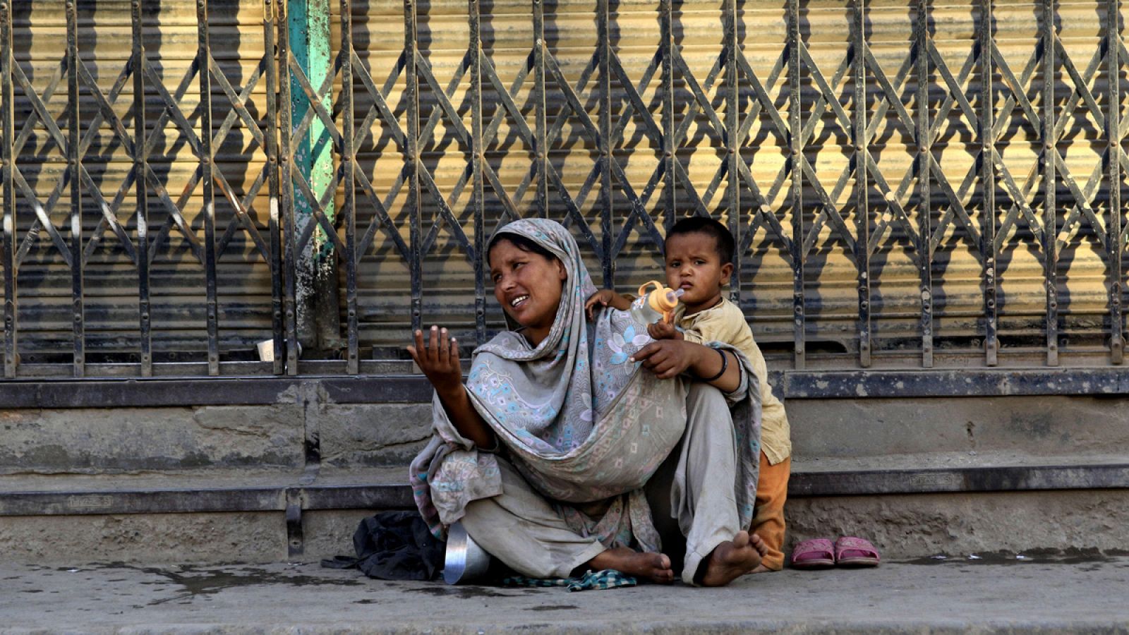 Una mujer pide limosna con su hijo en una calle de Peshawar
