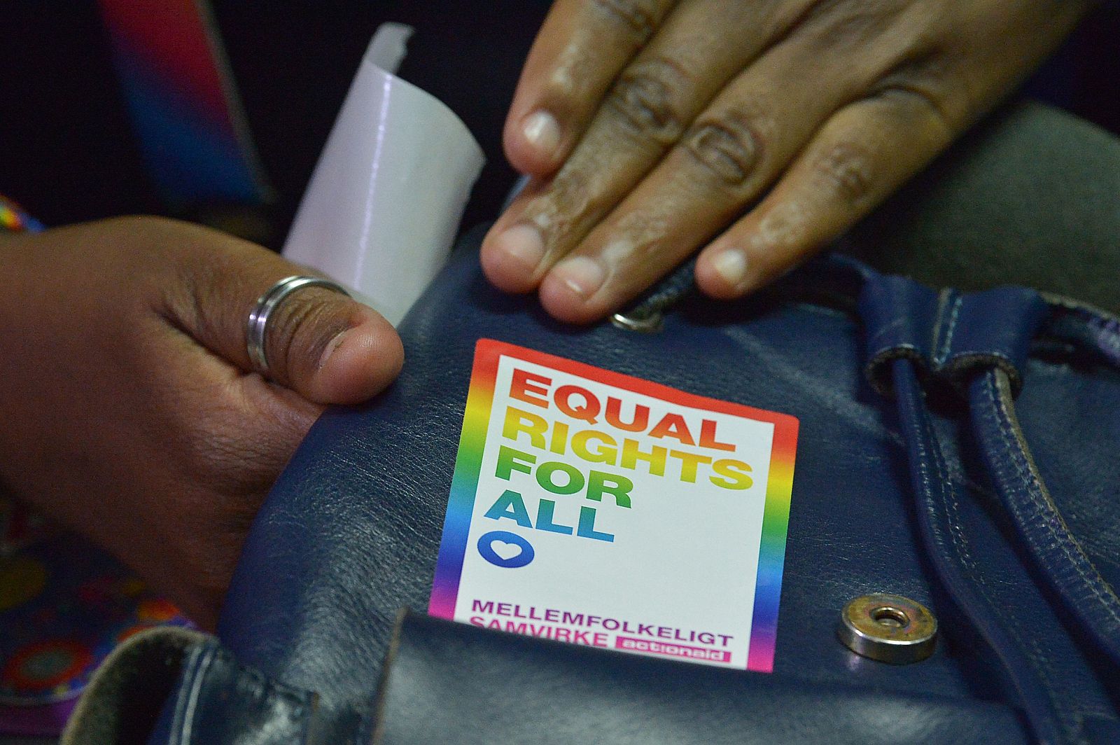Un acivista LGTB se coloca una pegatina reivindicando igualdad de derechos.