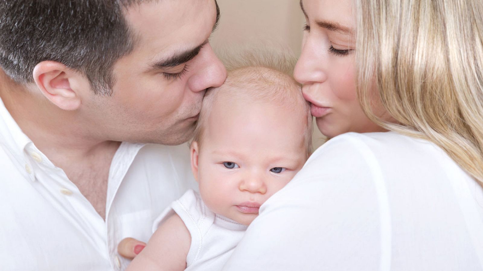 Un padre y una madre besan a su bebé