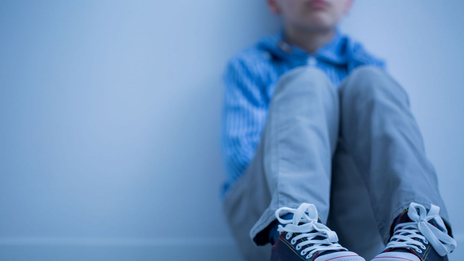 Imagen de un niño sentado solo en su habitación