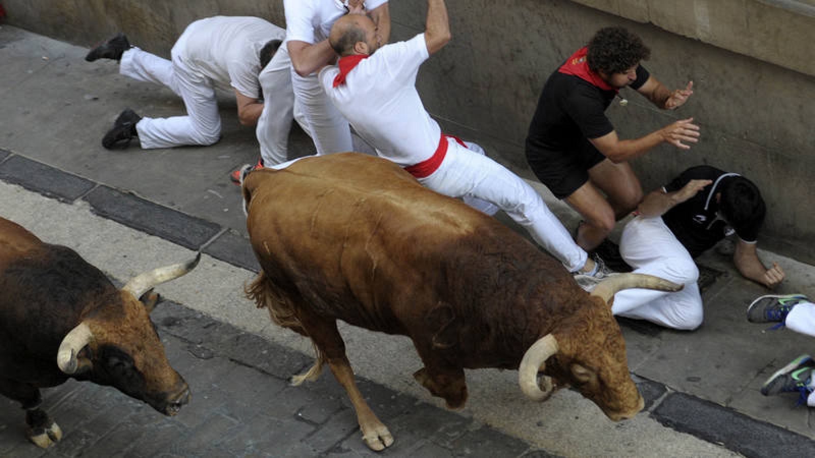 Un grupo de mozos cae ante un toro en los encierros de Sanfermines