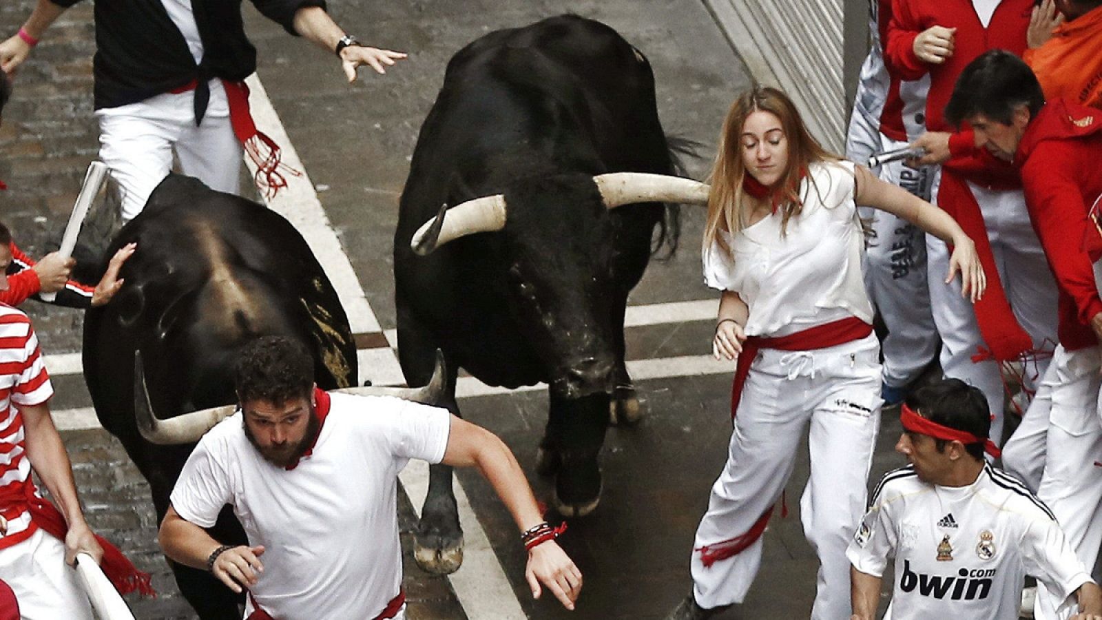 Una moza corre delante de los toros en Sanfermines