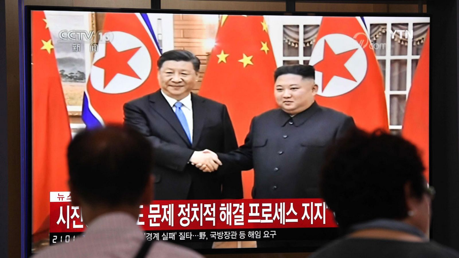 La gente ve una pantalla de noticias de televisión que muestra al líder norcoreano Kim Jong Un dándose la mano al presidente chino Xi Jinping, en la estación ferroviaria de Seúl