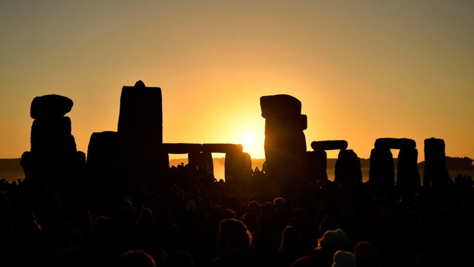 Varios entusiastas reciben el amanecer mientras participan en las celebraciones por el solsticio de verano en Stonehenge.