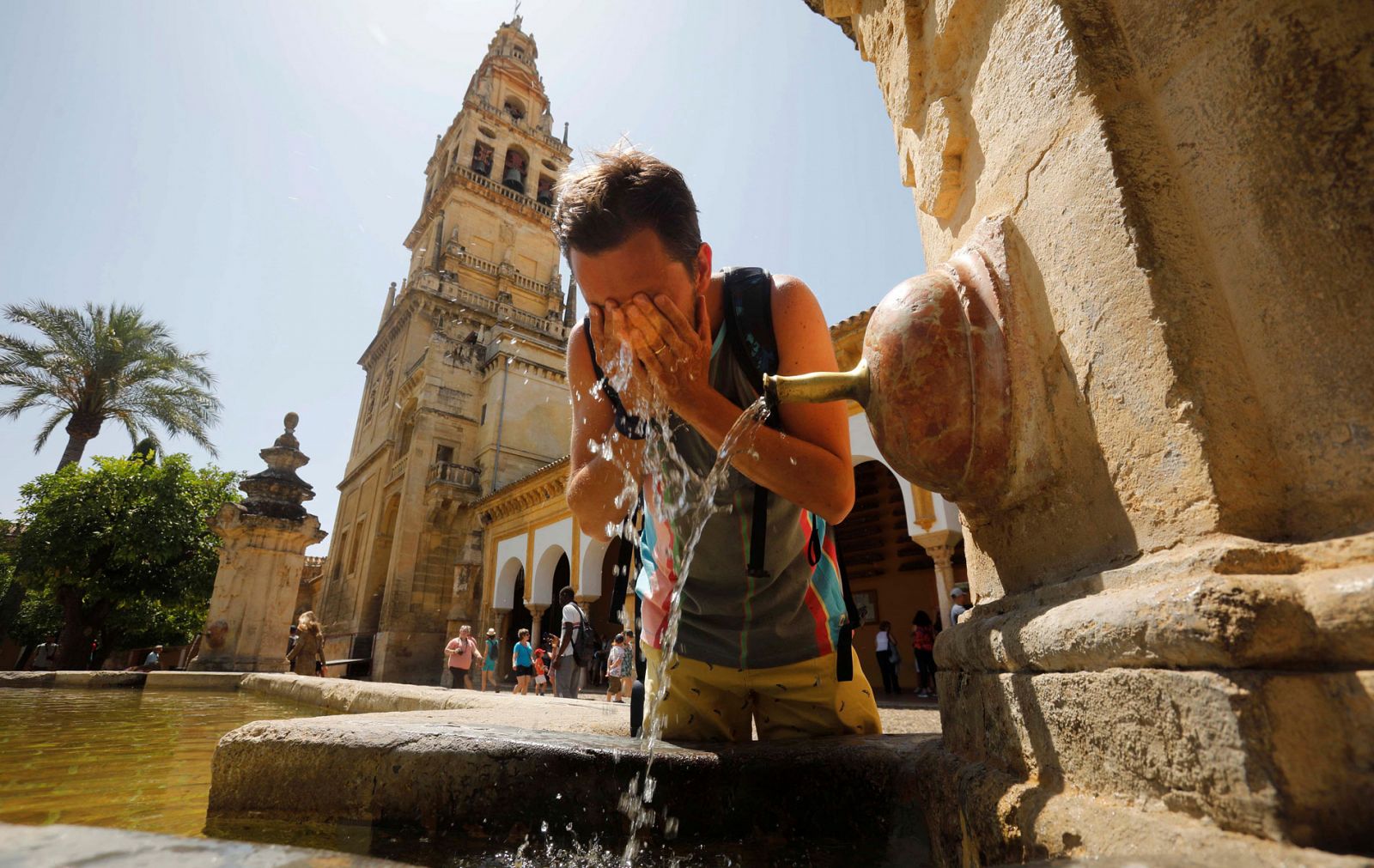 Un turista se refresca en una de las fuentes del patio de los Naranjos de la Mezquita-Catedral de Córdoba