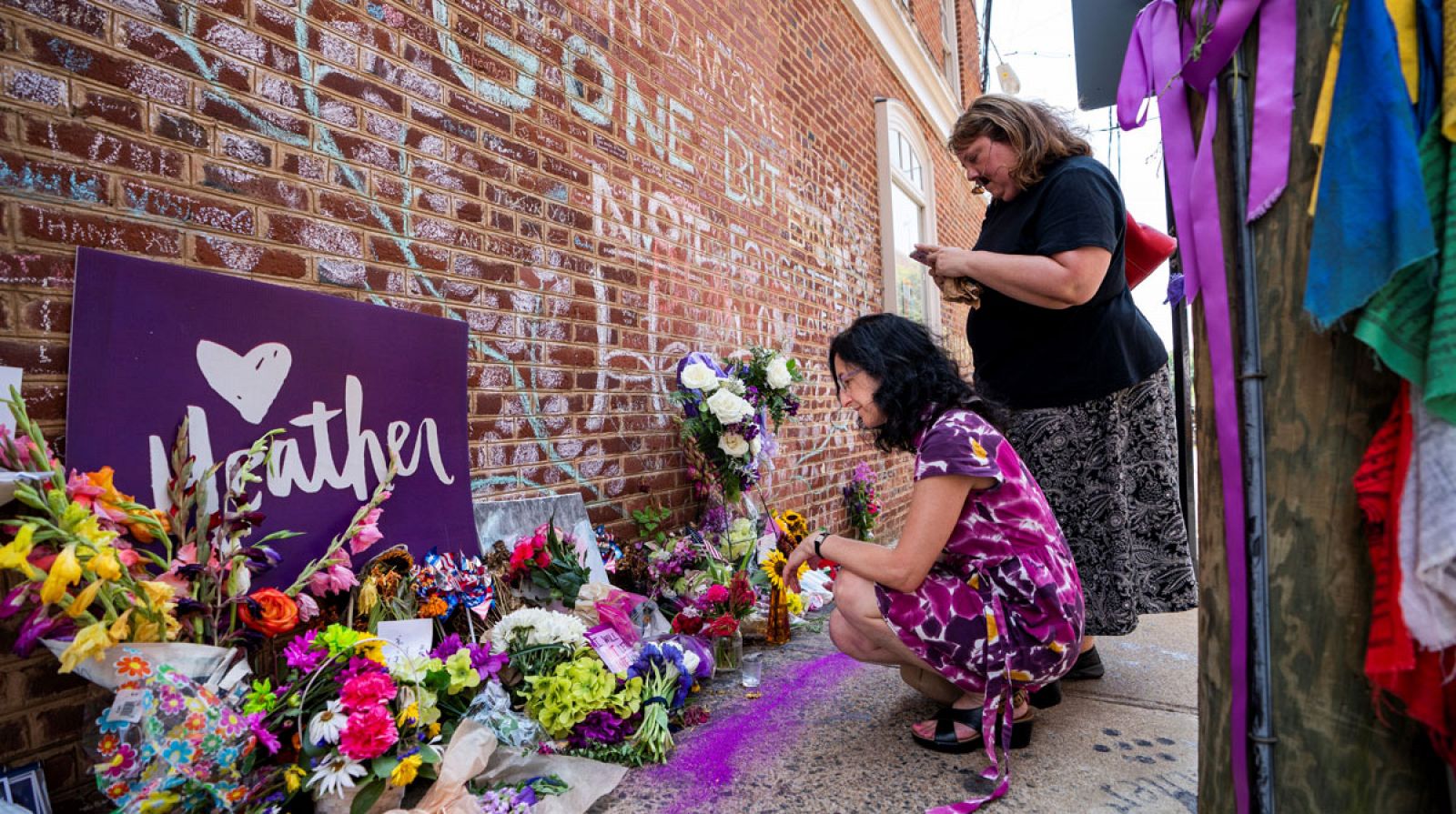 Varias mujeres colcan flores en el memorial de Heather Heyer, la mujer atropellada por un supremacista en una contraprotesta en 2017, en Charlottesville, Virginia (Estados Unidos).