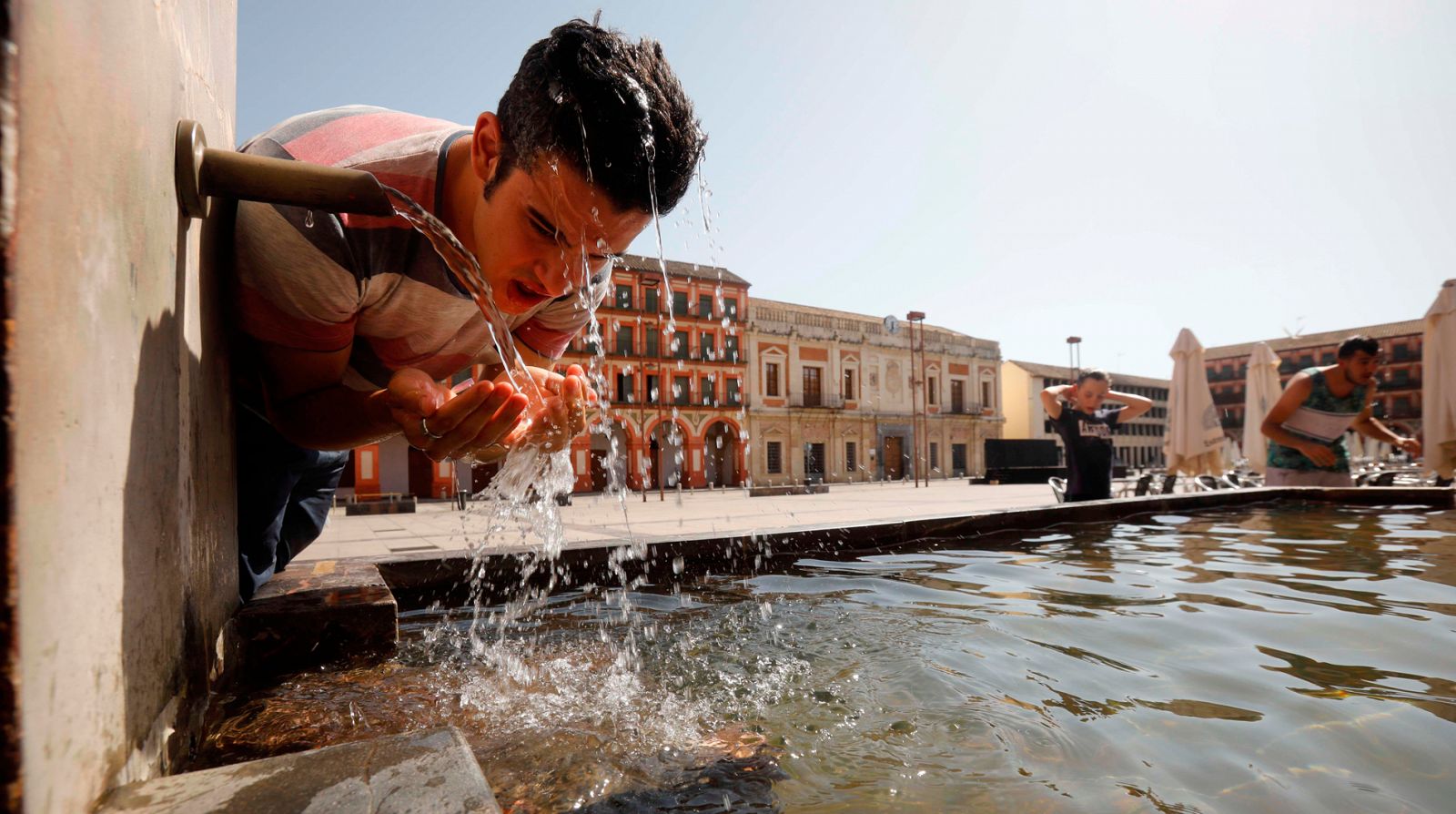 Un joven se refresca en la fuente del patio de los naranjos de la mezquita catedral de Córdoba este sábado. 