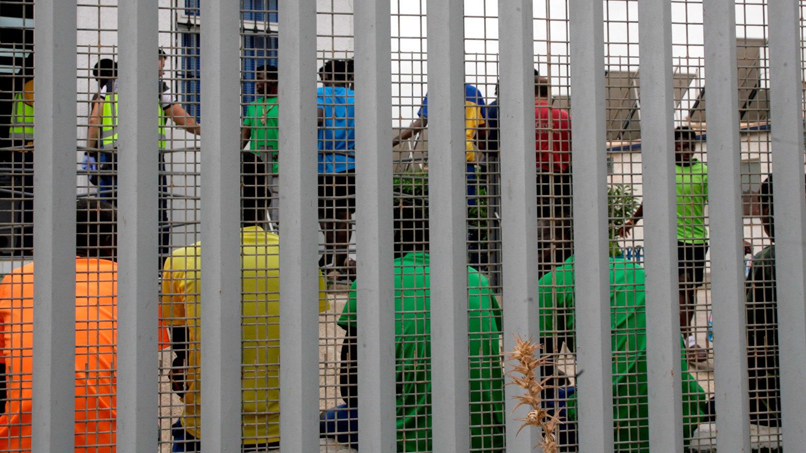 Un grupo de inmigrantes subsaharianos, tras el muro del Centro de Estancia Temporal de Inmigrantes (CETI)