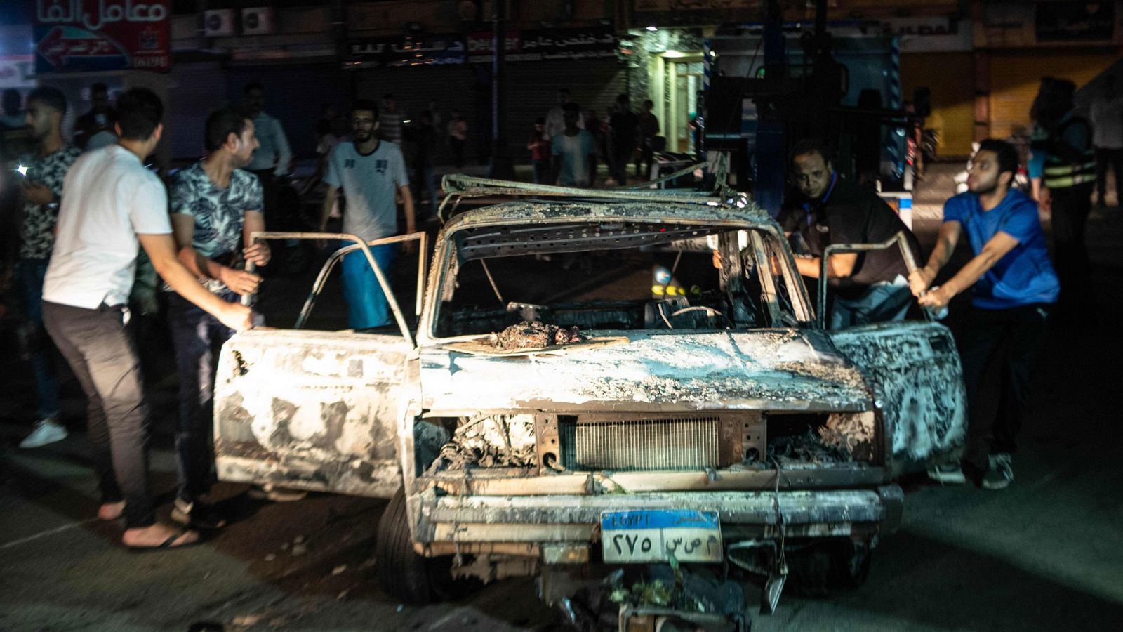 Varias personas rodean uno de los coches quemados en una explosión frente a un  hospital de El Cairo