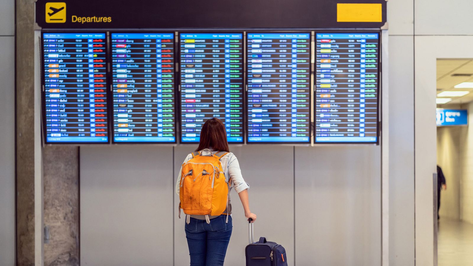 Una mujer observa las pantallas de Salidas en un aeropuerto