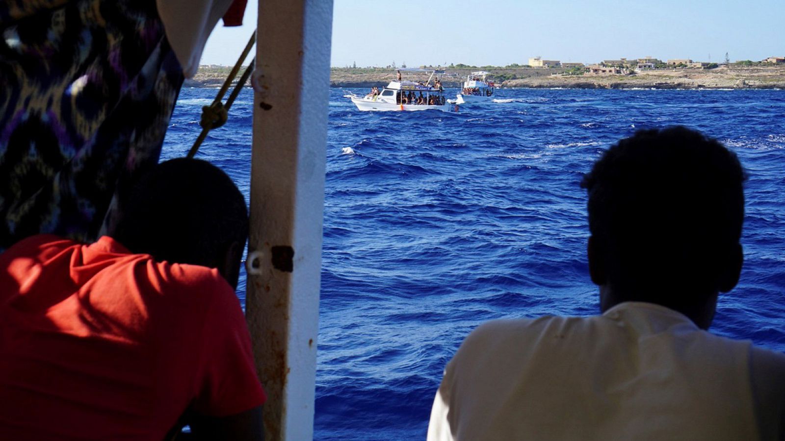 Algunos de los 107 migrantes en el interior del barco de la ONG española Open Arms, que sigue bloqueado desde hace 18 días junto a la isla italiana de Lampedusa. EFE/Francisco Gentico