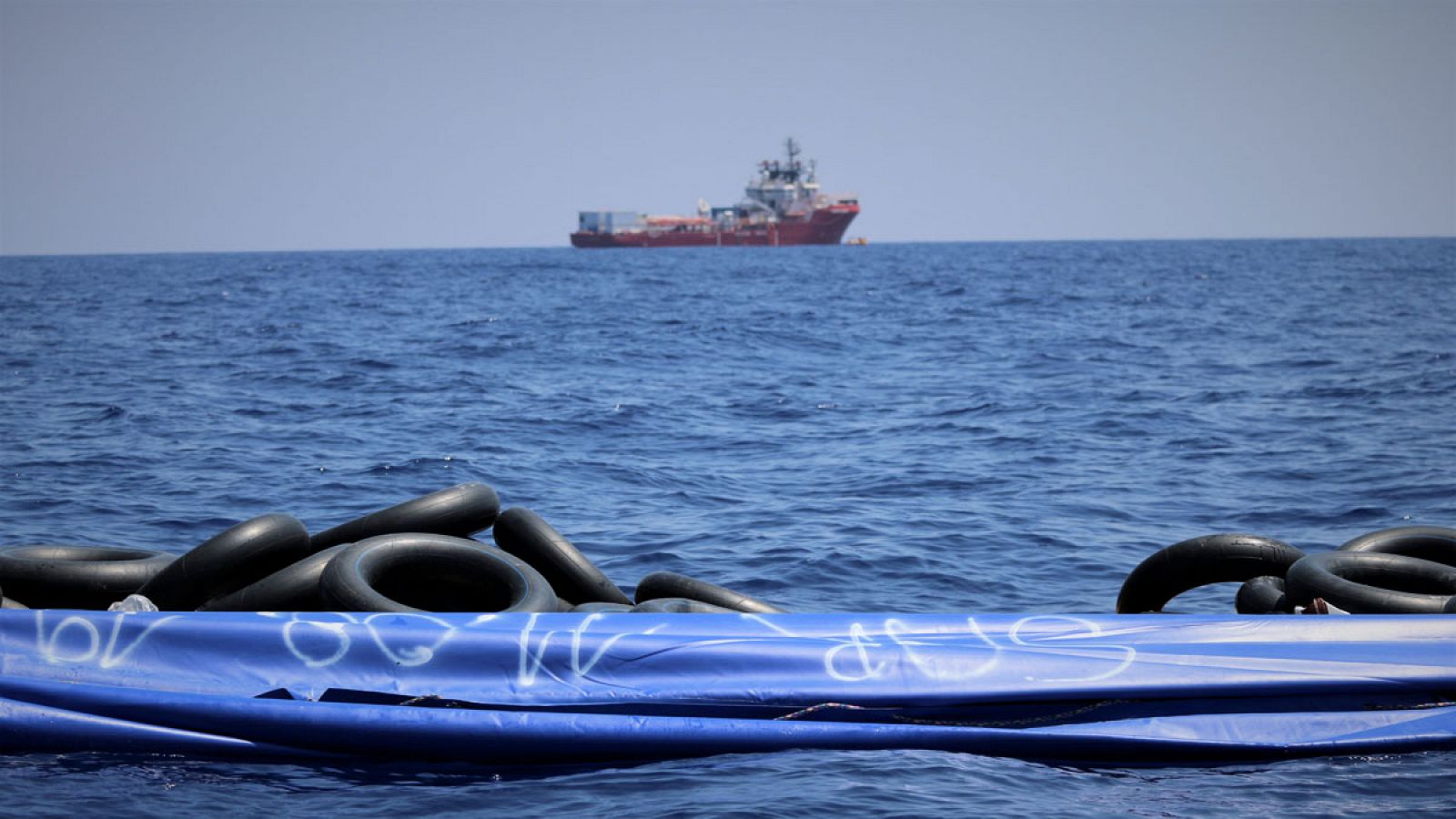 Una patera vacía flota en el Mediterráneo con el Ocean Viking en el horizonte