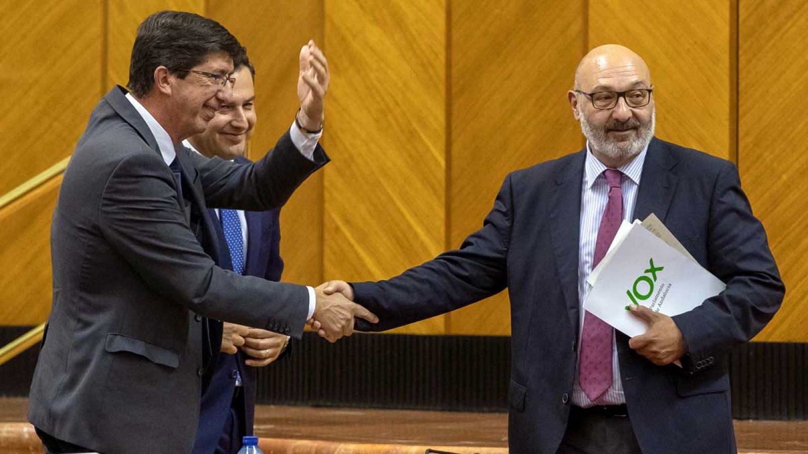 El vicepresidente de la Junta, Juan Marín (i), de Ciudadanos, hace un gesto a la bancada socialista mientras el presidente andaluz, Juanma Moreno y el portavoz de Vox, Alejandro Hernández (d), se dan la mano en el Parlamento de Andalucía