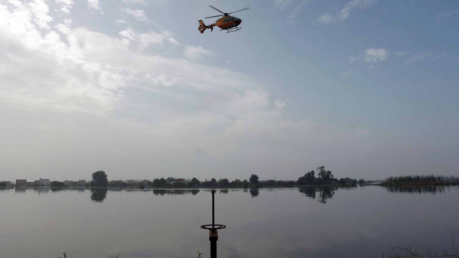 Gota fría: Un helicóptero busca en la zona donde el hombre desaparecido fue arrastrado por el agua en Dolores, Alicante.