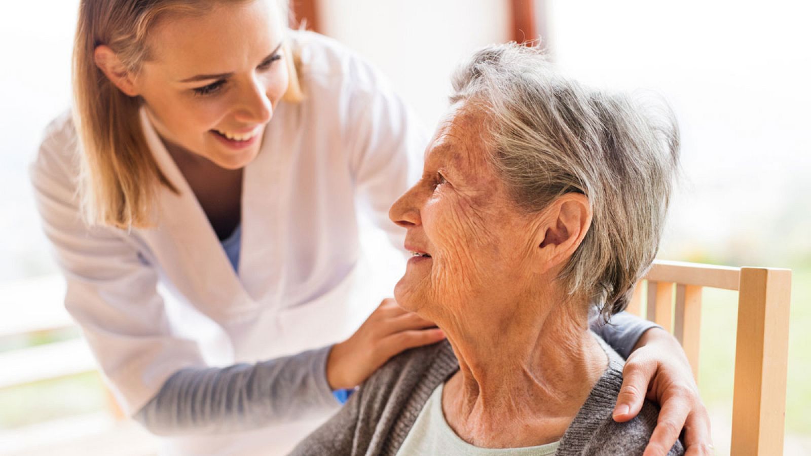 Una cuidadora atiende a una anciana dependiente