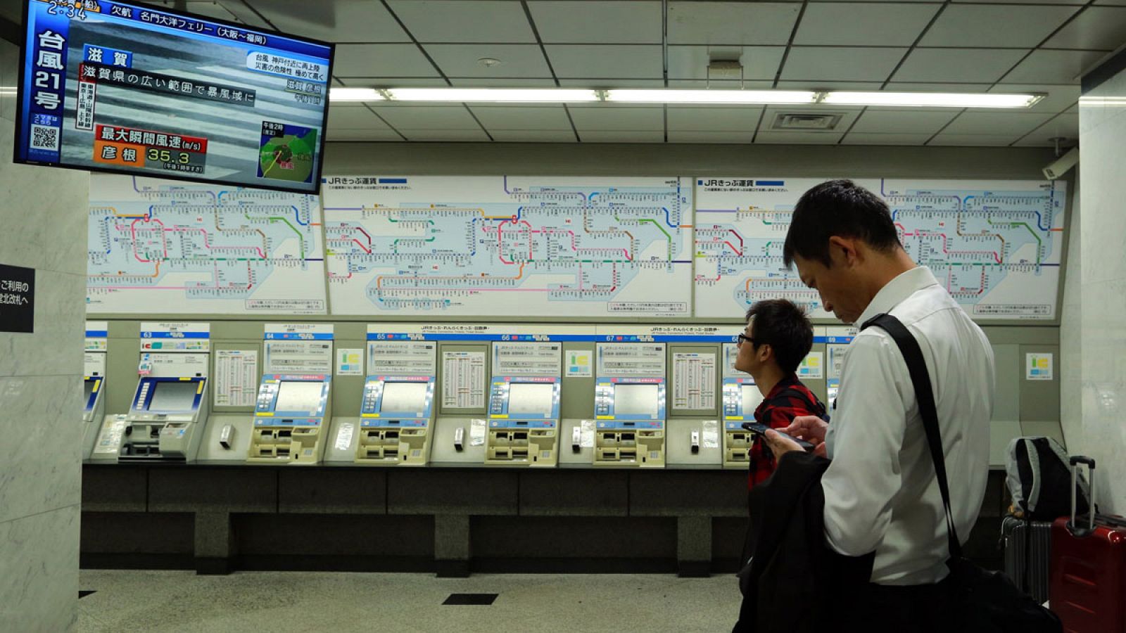 Imagen de septiembre de 2018 de dos pasajeros esperando el restablecimiento del servicio de trenes de la línea JR después de su cancelación como consecuencia del tifón Jebi, en Osaka, Japón.