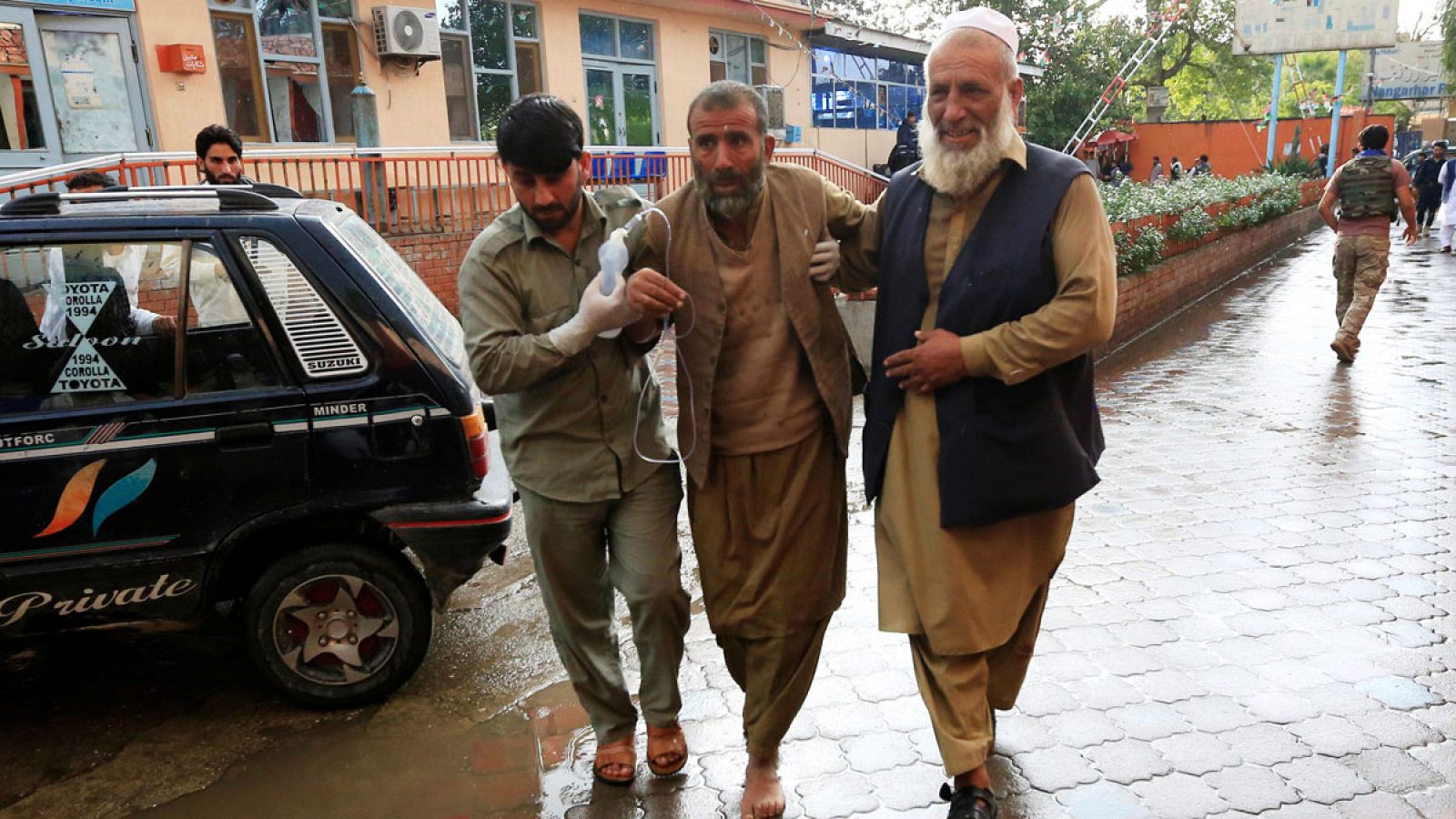 Dos hombres trasladan a un herido tras el ataque a una mezquita en Afganistán
