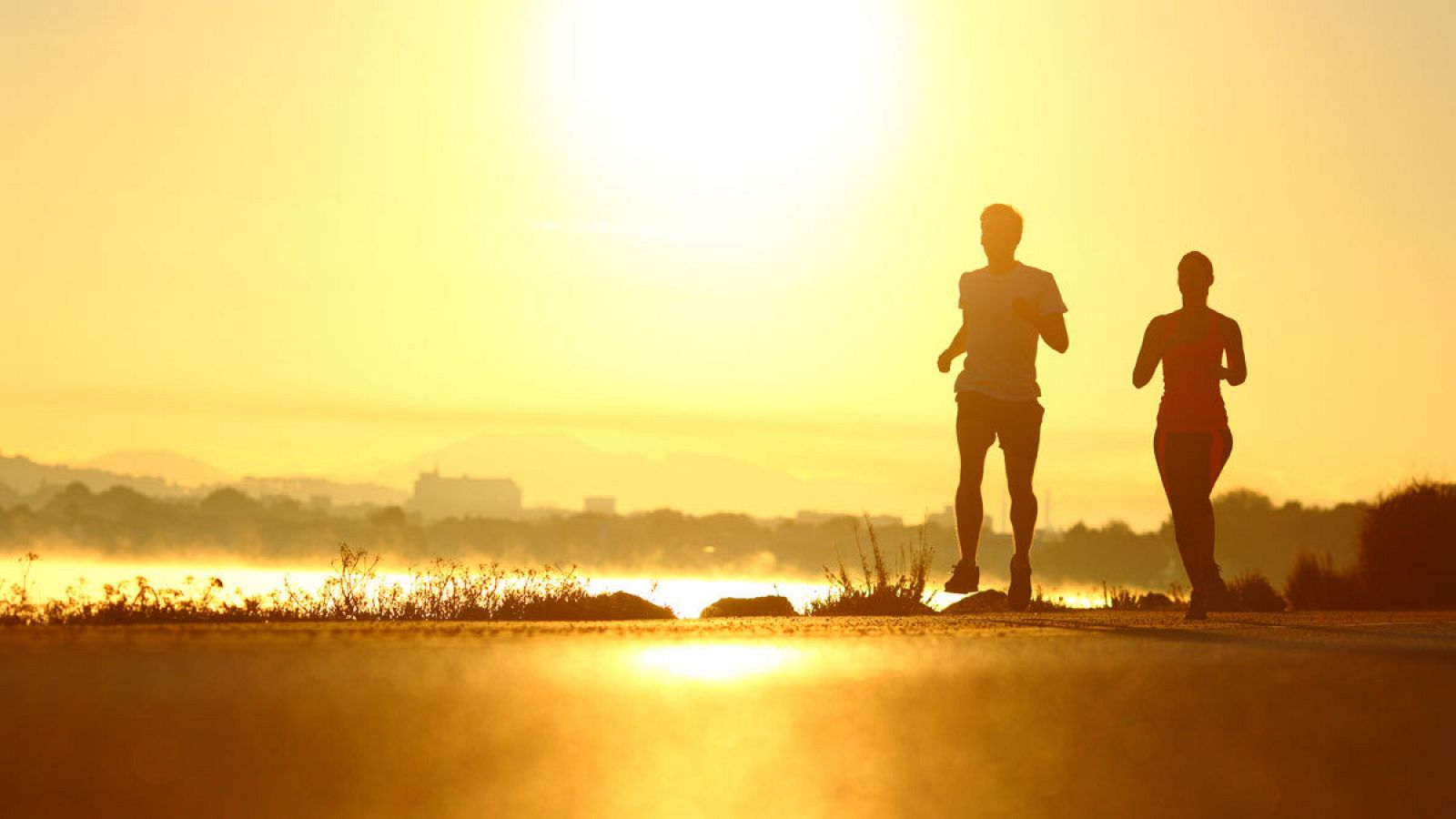 Un hombre y una mujer corren hacen deporte a la salida del sol