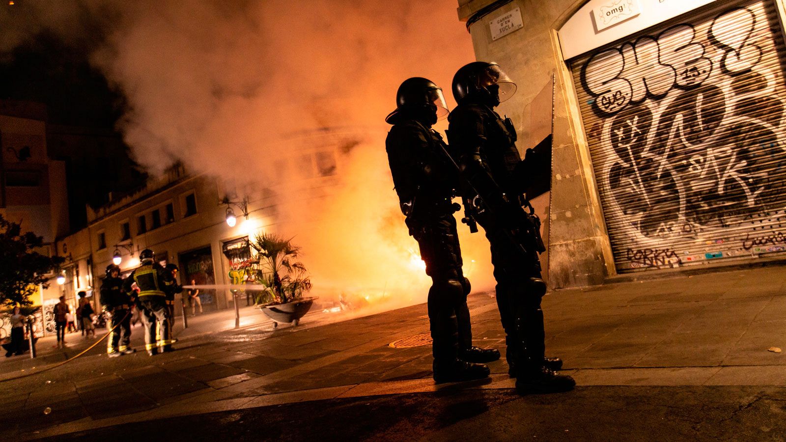 Mossos d'Esquadra controlan una calle de El Raval mientras los bomberos apagan una barricada de fuego