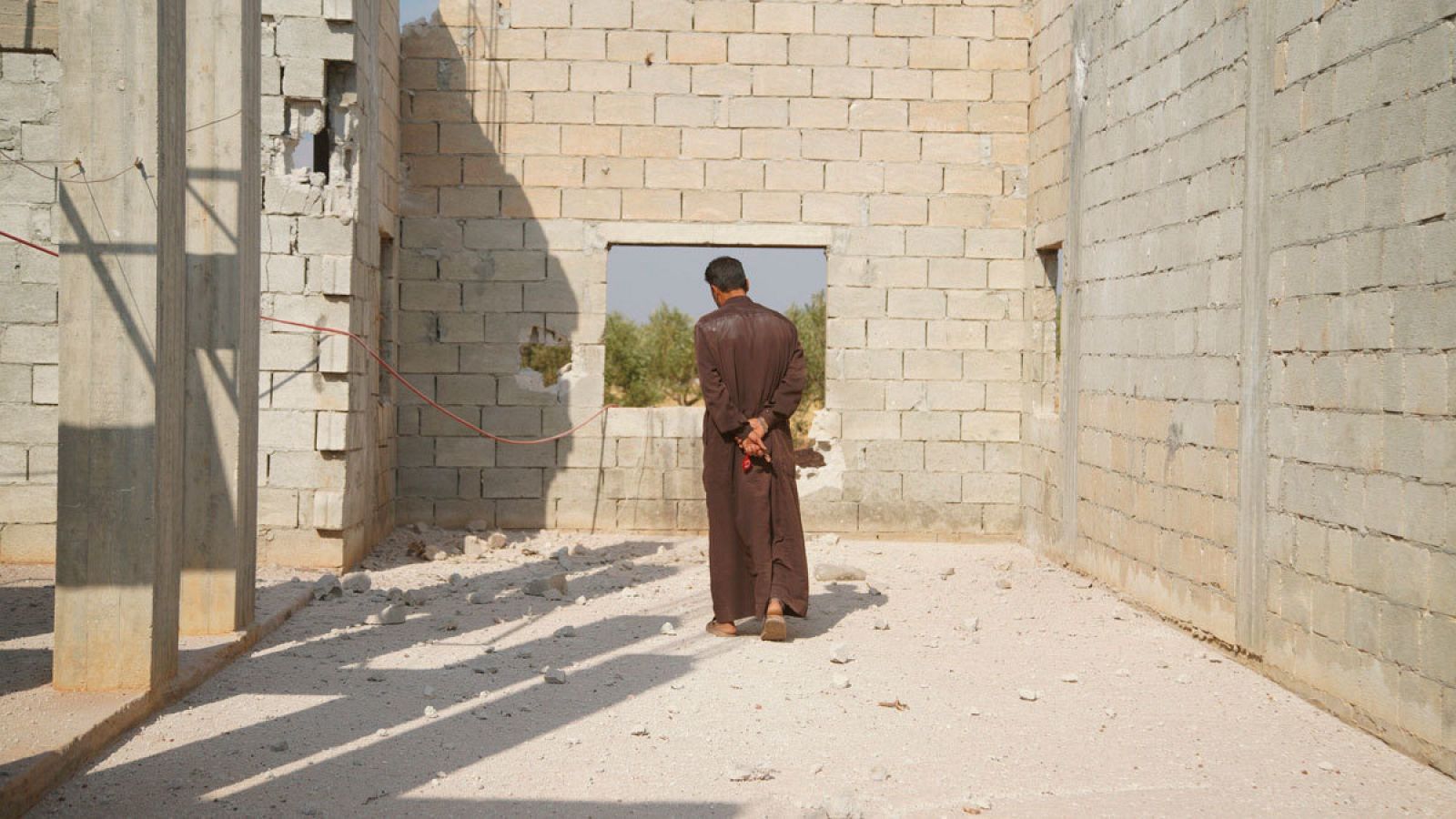 Un hombre examina los restos del edificio bombardeado por las fuerzas estadounidenses en el que murió el líder del Estado Islámico, Abu Bakr al Bagdadi